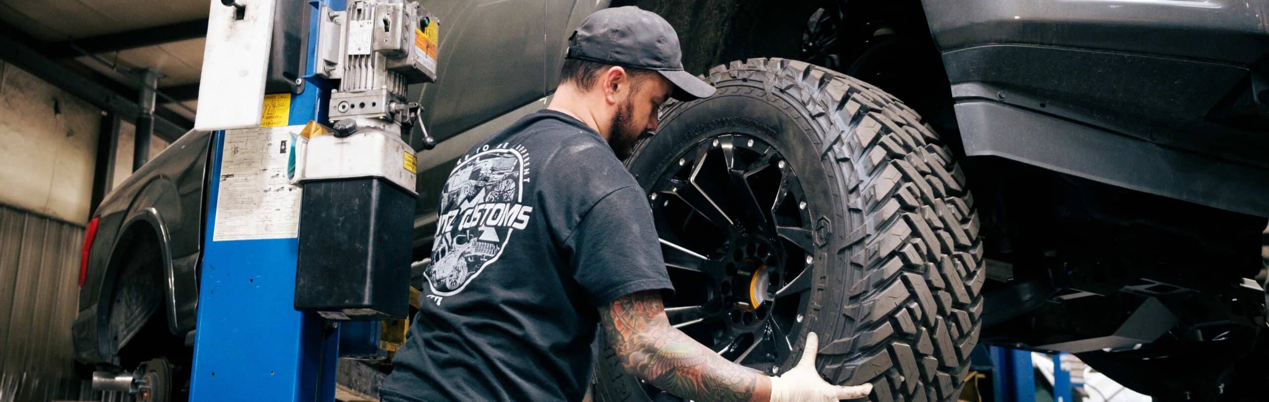 Krietz technician fitting a wheel and tire to a vehicle on a lift